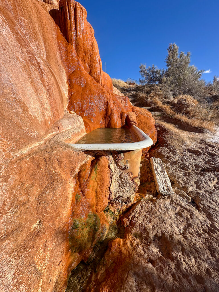 A private cast iron soaking tub next to a sandstone boulder at Mystic Hot Springs in Monroe, Utah.