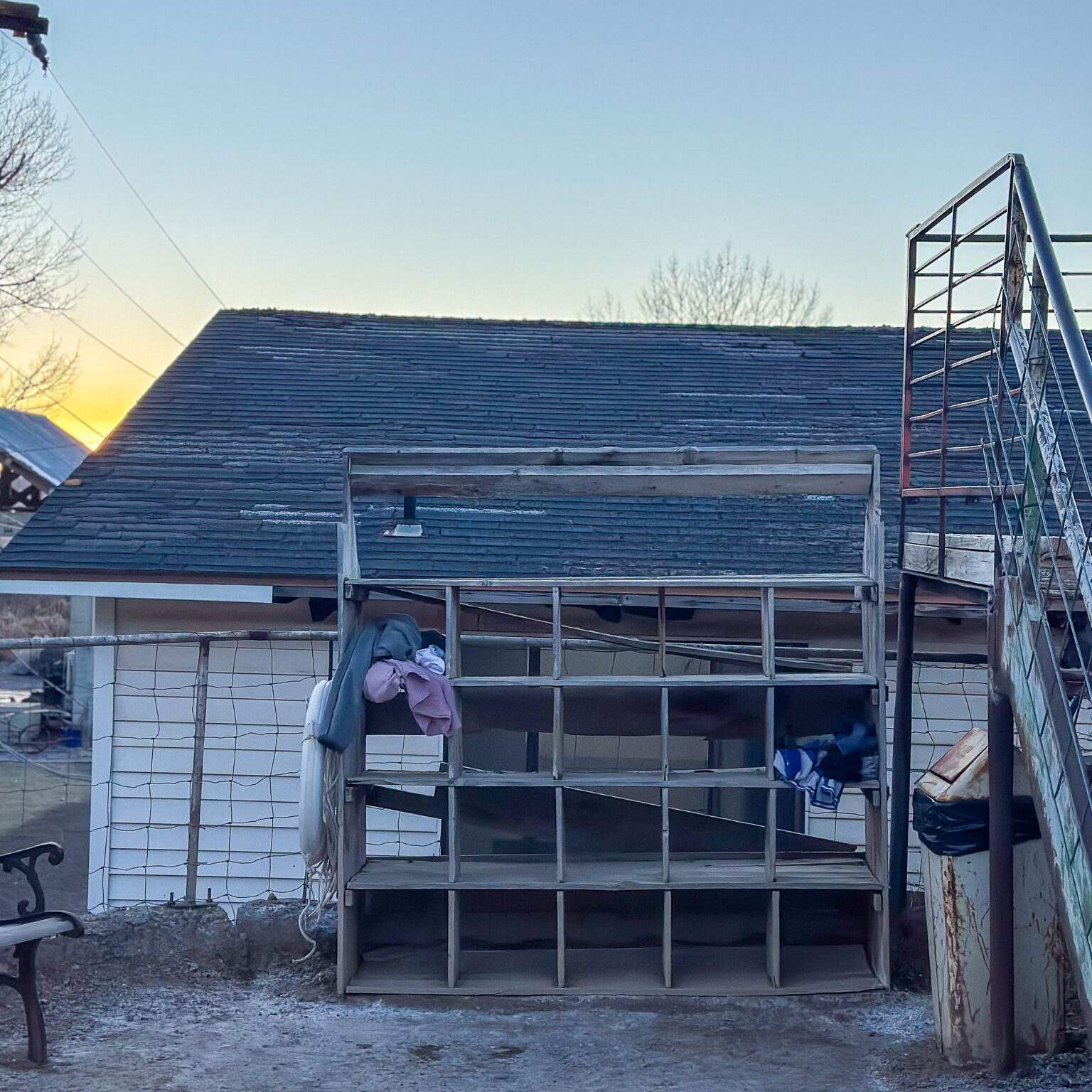 A shabby wooden cubby shelf in front of a building.